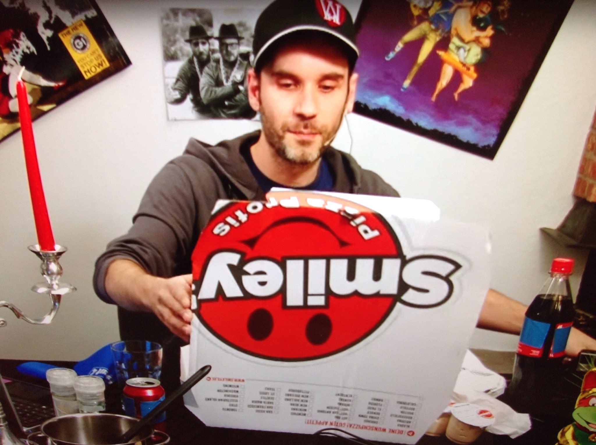 Foto eine RocketBeans Moderators auf dem er im RocketBeans Studio einen Smiley's Pizzakarton öffnet